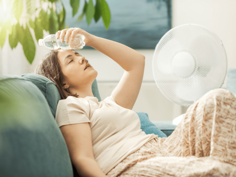 Woman cools down next to a white fan