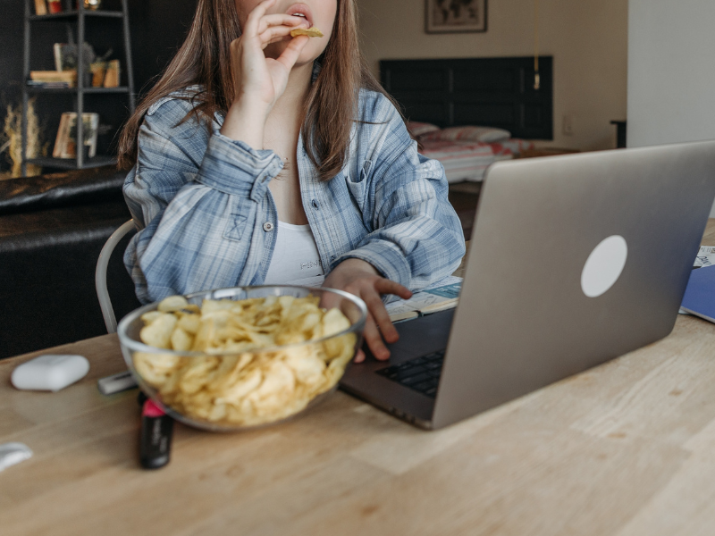 Woman eating chips and using a laptop