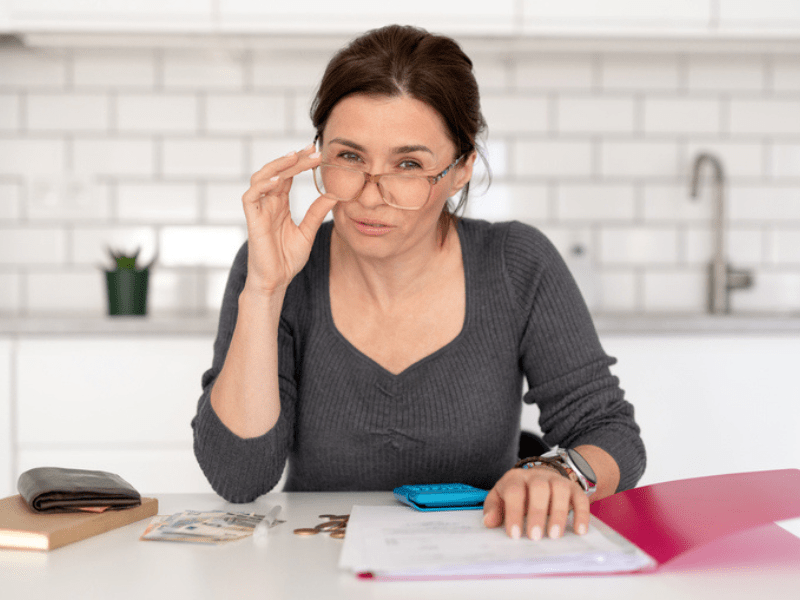 Woman goes through her finances while sitting in a kitchen