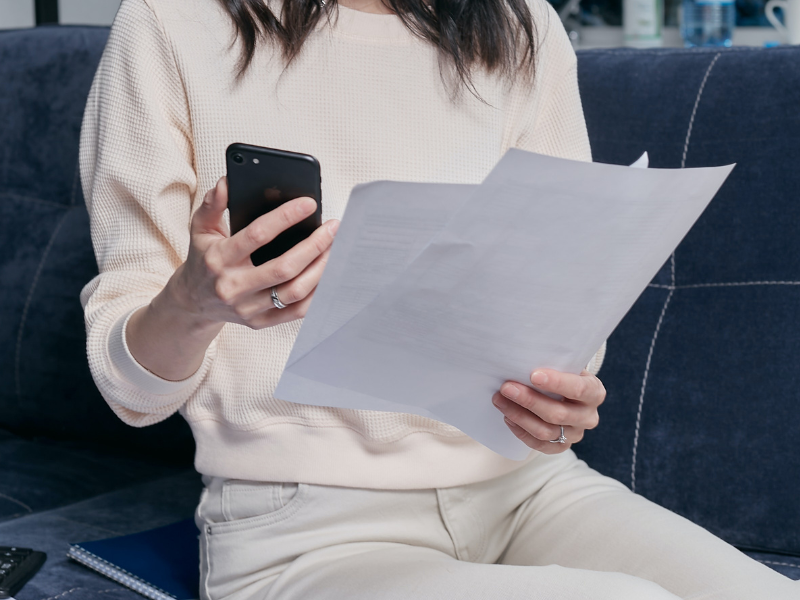 Woman holding documents and smartphone in hands