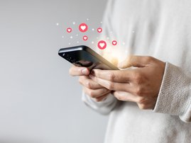 Woman holding a smartphone displaying heart emojis