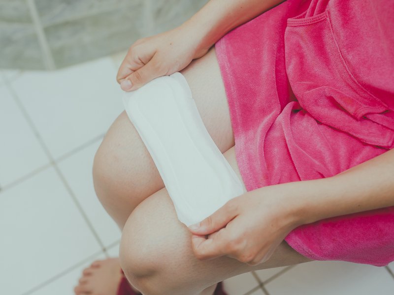 Woman in a toilet with a sanitary napkin.
