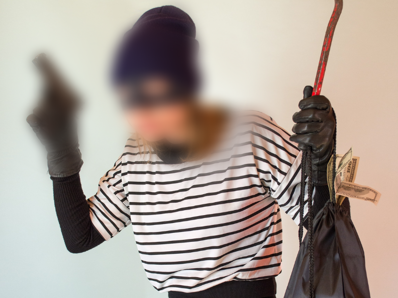 Woman in striped shirt is wearing a beanie and holding a firearm and bag of cash
