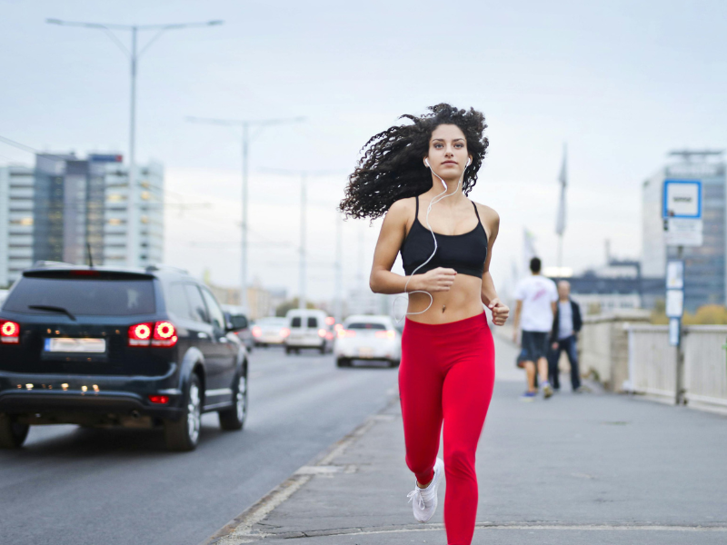Woman listening to music on earphones running on sidewalk