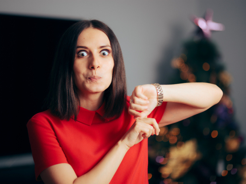 Woman pointing to her watch on Christmas eve