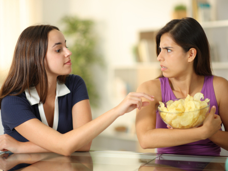 Woman protecting her potato chips from a friend