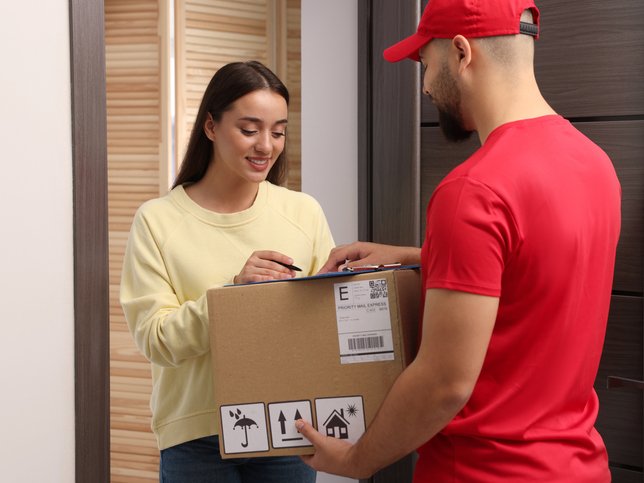 Woman signing for delivered parcel at home