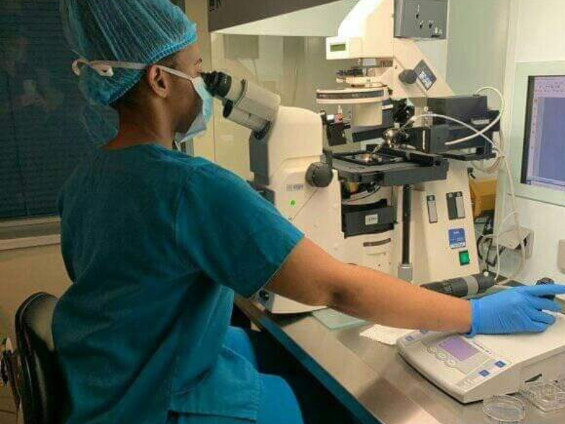 Woman sitting in a lab using a microscope