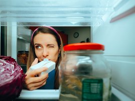 Woman smelling a milk carton to see if it has expired
