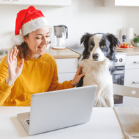 Woman wearing Santa hat sits in a kitchen with her dog