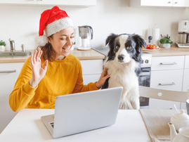 Woman wearing Santa hat sits in a kitchen with her dog
