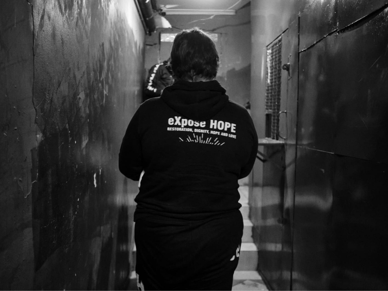 Woman wearing a black hoodie in a dark hallway
