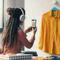 Woman wearing headphones takes pictures of her clothes in a bedroom