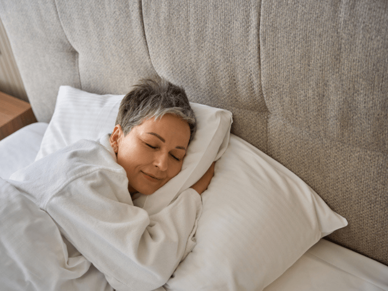 Woman with grey hair sleeping peacefully in a bed