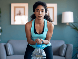 Woman working out at home using water bottle as weight