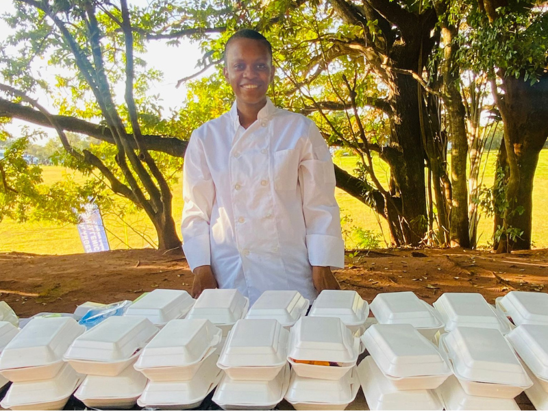 Young female chef standing at a table with packed food