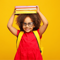 Young school kid with glasses smiles while holding books on her head