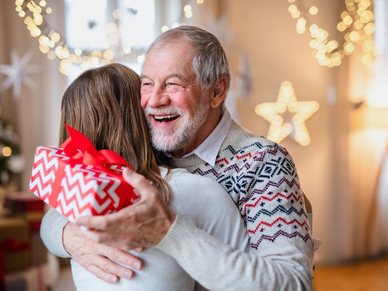 Young woman giving present to happy grandfather