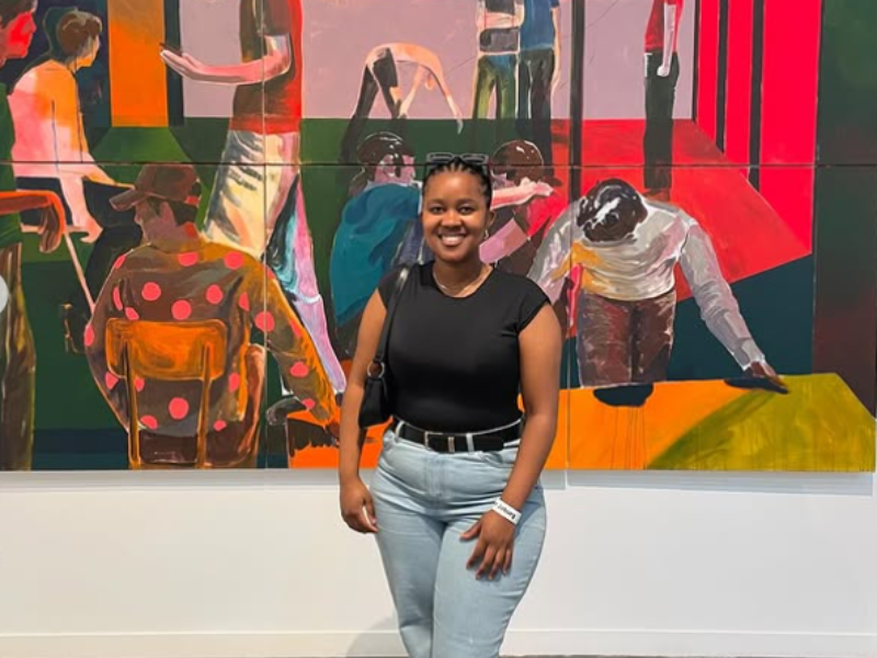 Zimkhitha Xwashu poses in front of a painting