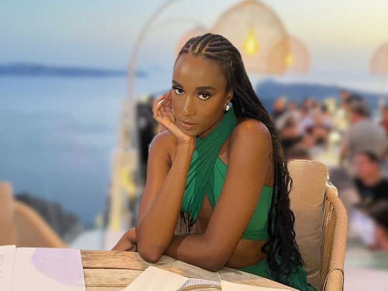 Zozibini Tunzi sitting at a restaurant table with an ocean view