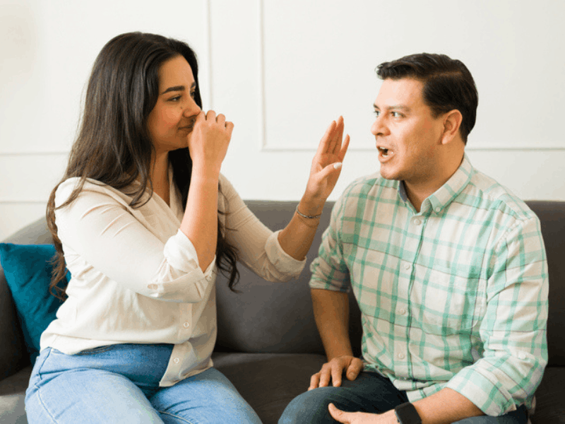 Woman blocks her nose and avoids her boyfriends bad breath