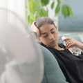 woman sitting next to an electric fan