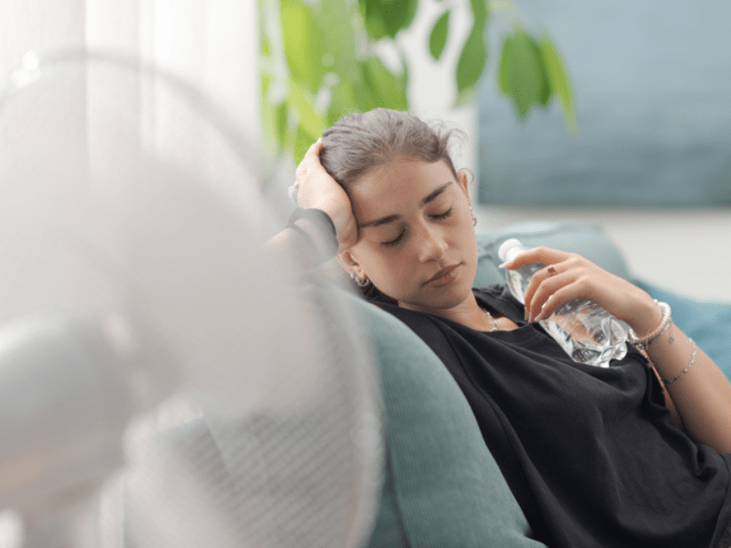 woman sitting next to an electric fan
