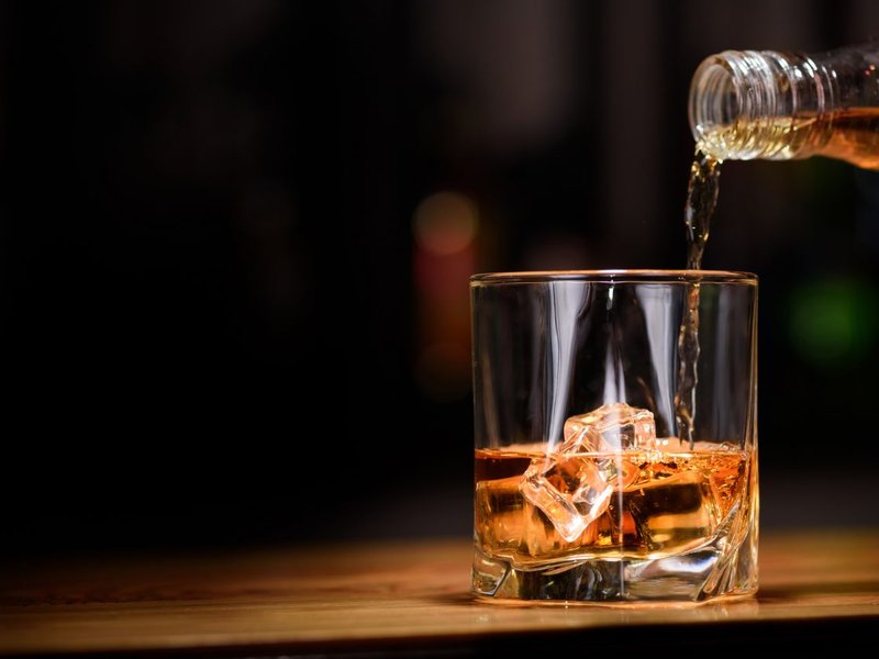Man pouring whiskey in to glass/ iStock