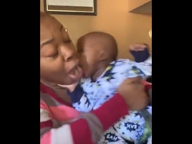 A baby biting his mom on the mouth