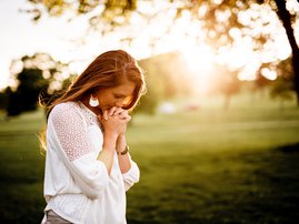 woman praying in the woods