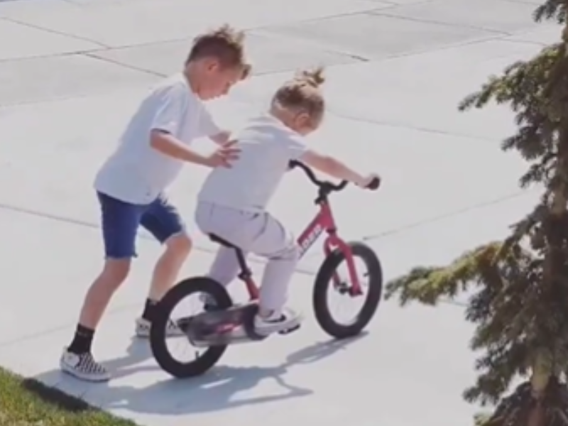 Brother teaching his sister how to ride a bike