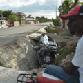 A car damaged by a bus lies on the side of a road after hit-and-run in Haiti