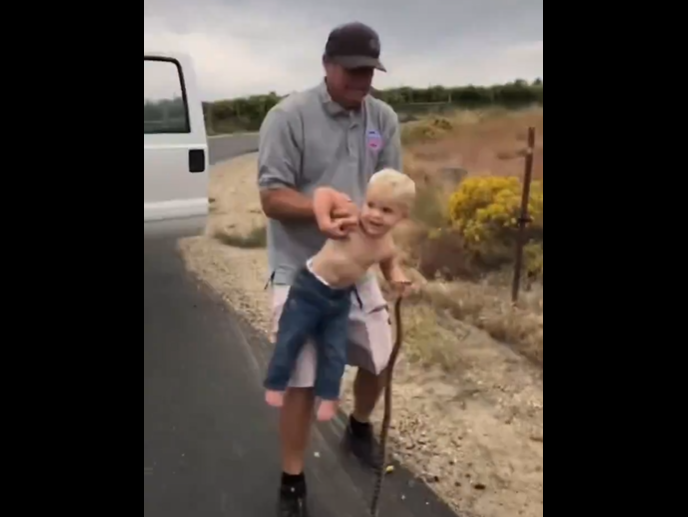 Child playing with a snake/ Twitter