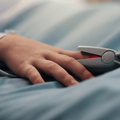 close up of hand with pulse oximeter on a hospital bed