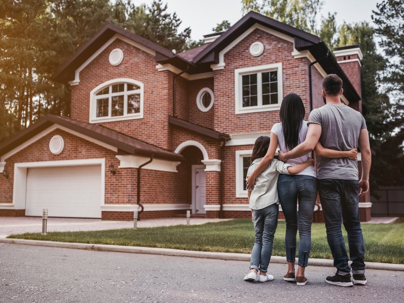 Couple and child in front of house