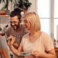 couple wearing glasses paint on easel