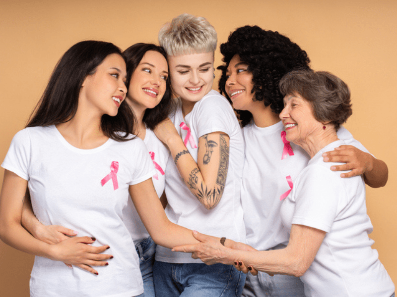 Diverse women wearing white t-shirts and pink ribbons