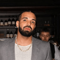drake poses in front of a bar