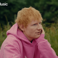 Ed sheeran wearing a pink hoodie with a Play icon
