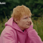 Ed sheeran wearing a pink hoodie with a Play icon