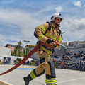 firefighter carrying a fire hose during intense training