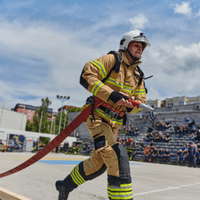 firefighter carrying a fire hose during intense training