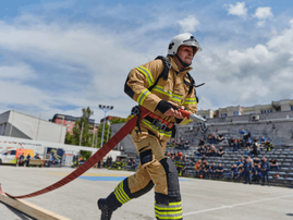 firefighter carrying a fire hose during intense training