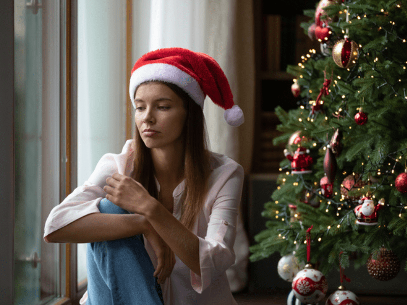 frustrated woman sits next to a Christmas tree