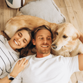 happy couple lie next to a golden retriever dog