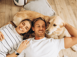 happy couple lie next to a golden retriever dog
