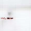 Man hiding behind white blinds