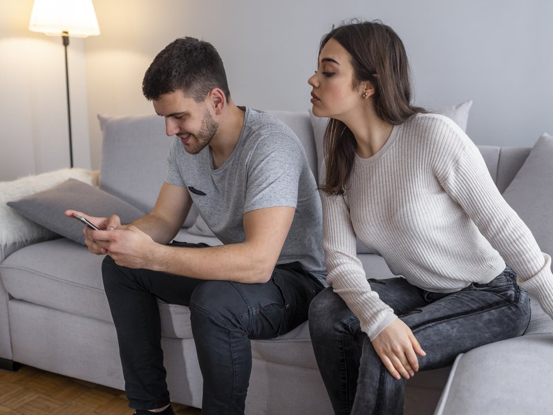 A man looking at his phone and woman looking who he is talking to