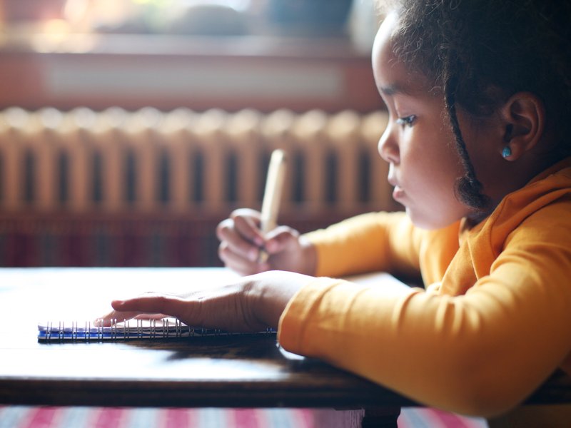 Young girl writing in a book / iStock