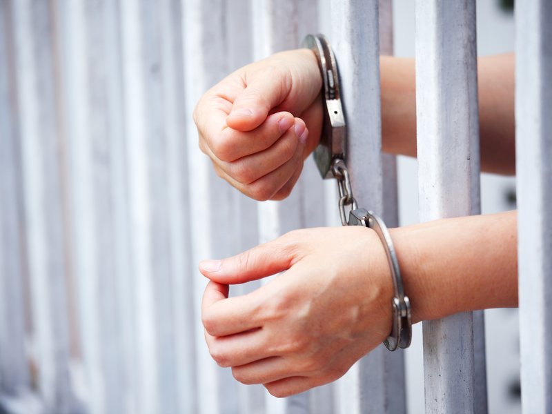 Hands of prisoner in bar jail background